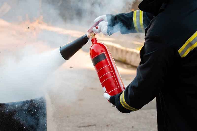 homme qui éteint un feu avec des extincteur à lyon poser par hestia securité